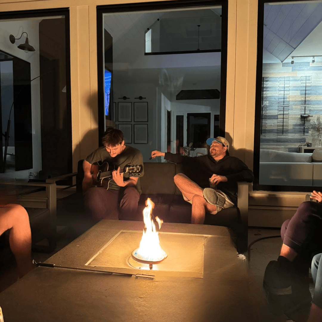 A guitar being played around a fire at night